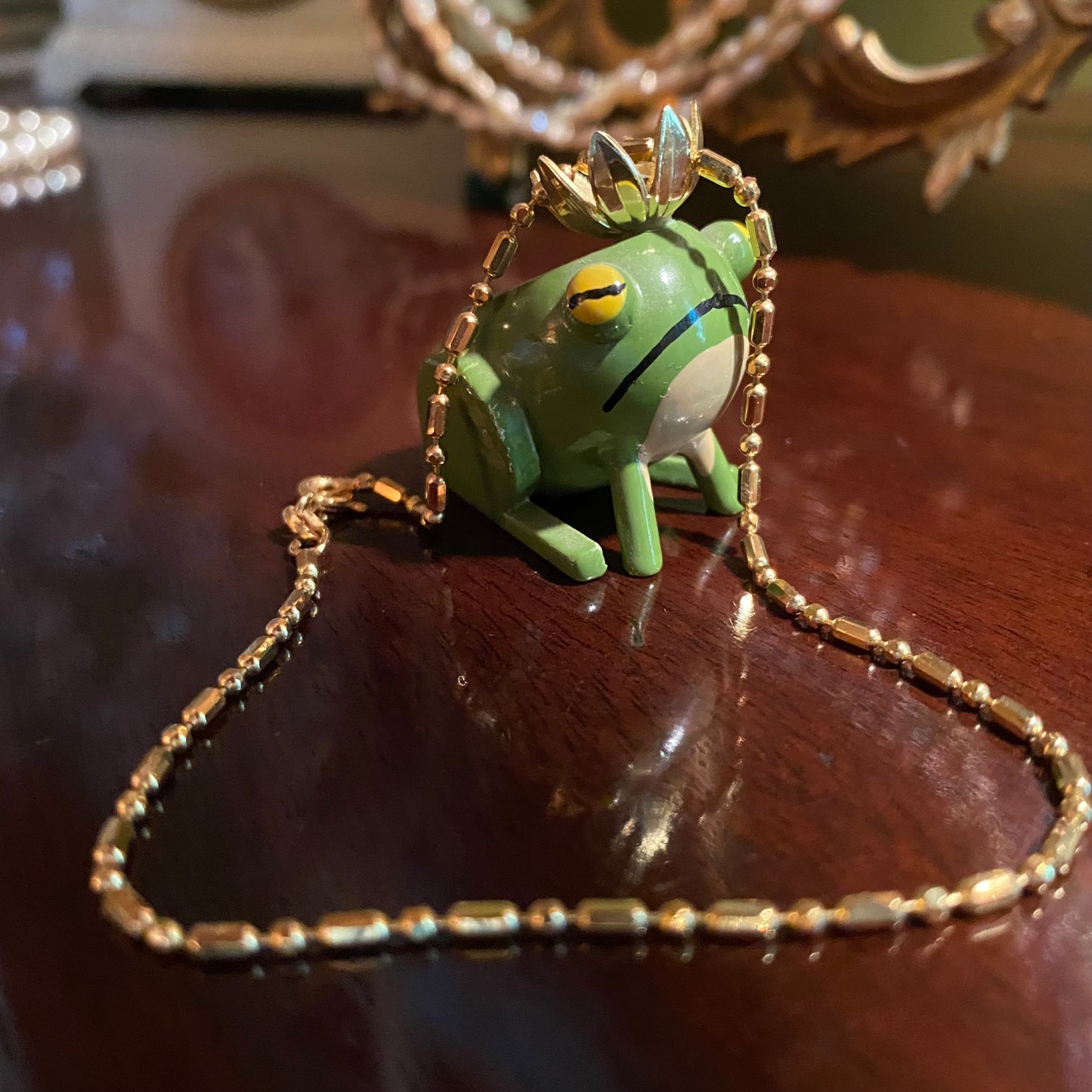 Yellow gold anklet on wooden frog with a crown