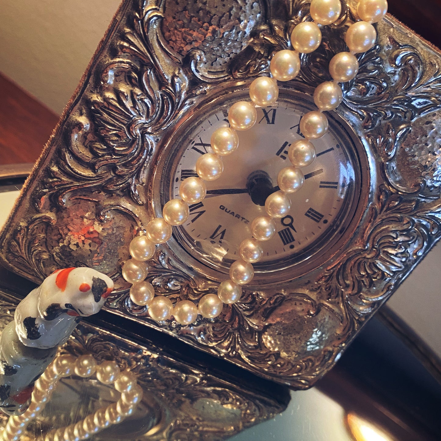 Pearl choker hanging over a silver framed clock